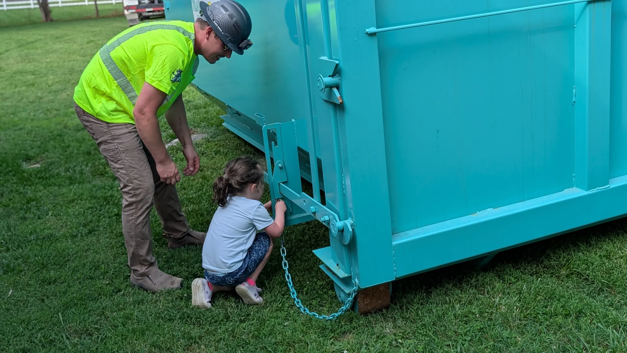 William Shackelford securing the doors on a Trash Pandy dumpster with his daughter helping